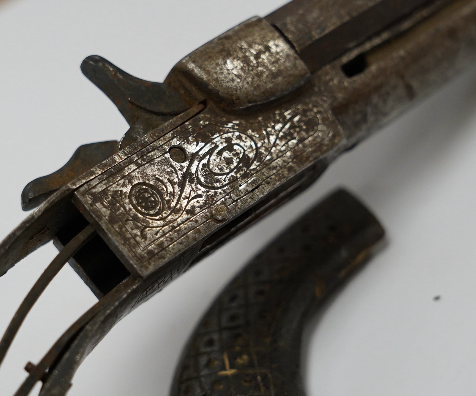 An early 19th century double-barrelled breach loading percussion pistol in relic condition, steel barrels, engraved frame, and walnut two piece grip, one piece missing, one piece detached, folding triggers, both missing